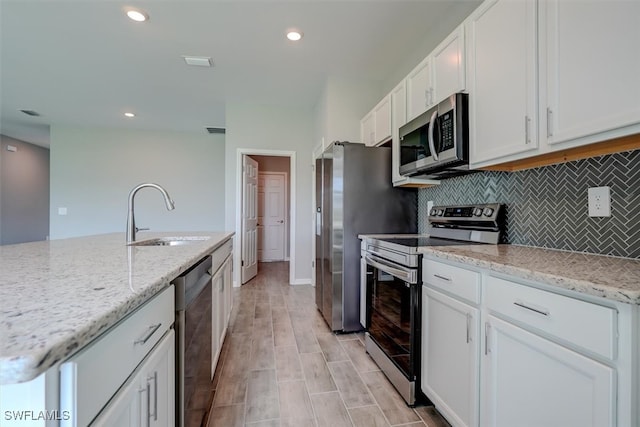 kitchen with light stone counters, sink, light hardwood / wood-style flooring, white cabinetry, and stainless steel appliances