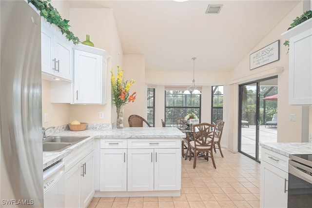 kitchen with light tile patterned floors, kitchen peninsula, white appliances, white cabinetry, and vaulted ceiling