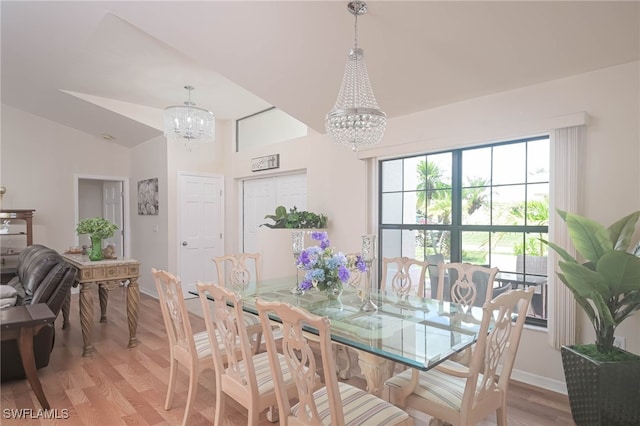 dining area featuring light wood-type flooring, a chandelier, and vaulted ceiling