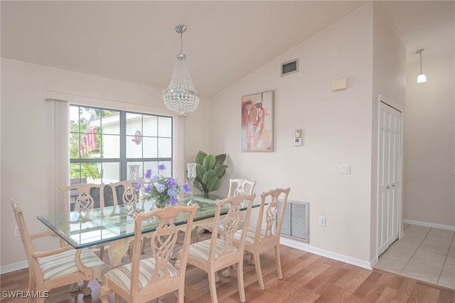 dining room with a notable chandelier, light hardwood / wood-style floors, and high vaulted ceiling