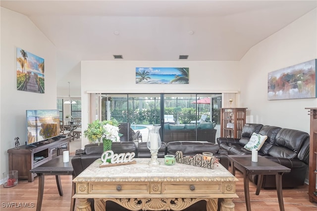 living room with wood-type flooring, vaulted ceiling, and plenty of natural light