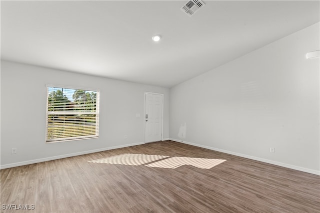 empty room with hardwood / wood-style flooring and vaulted ceiling