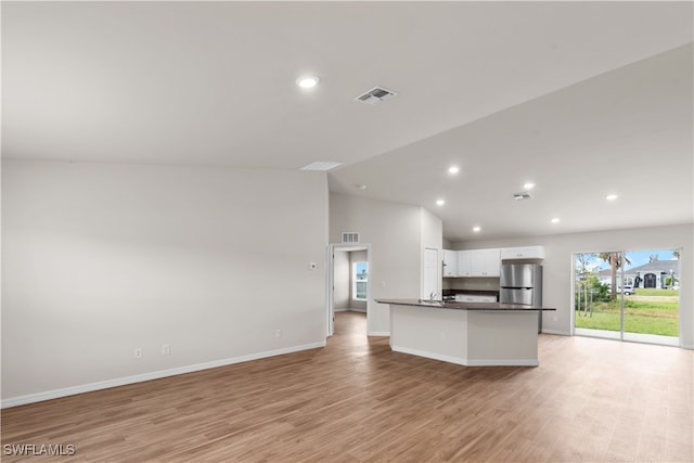 kitchen with white cabinetry, stainless steel fridge, light wood-type flooring, and vaulted ceiling