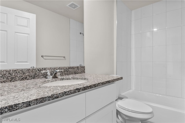 full bathroom with tiled shower / bath, vanity, and toilet