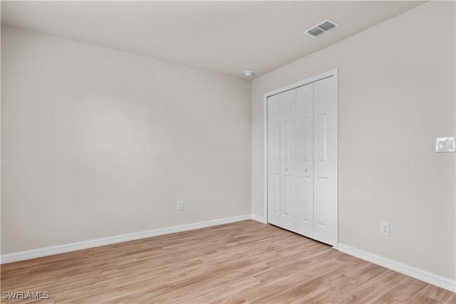 unfurnished bedroom with light hardwood / wood-style flooring and a closet