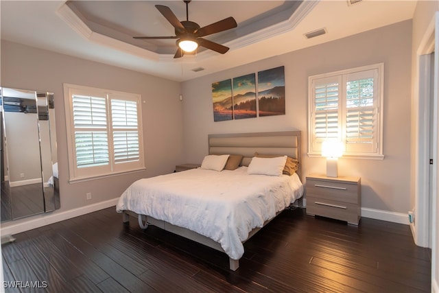 bedroom with dark hardwood / wood-style flooring, a raised ceiling, and ceiling fan