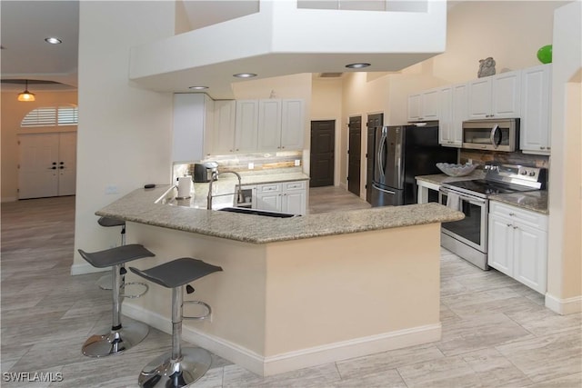 kitchen featuring white cabinetry, appliances with stainless steel finishes, kitchen peninsula, and backsplash