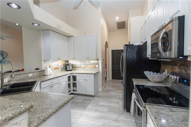 kitchen featuring decorative backsplash, kitchen peninsula, stainless steel appliances, sink, and white cabinetry