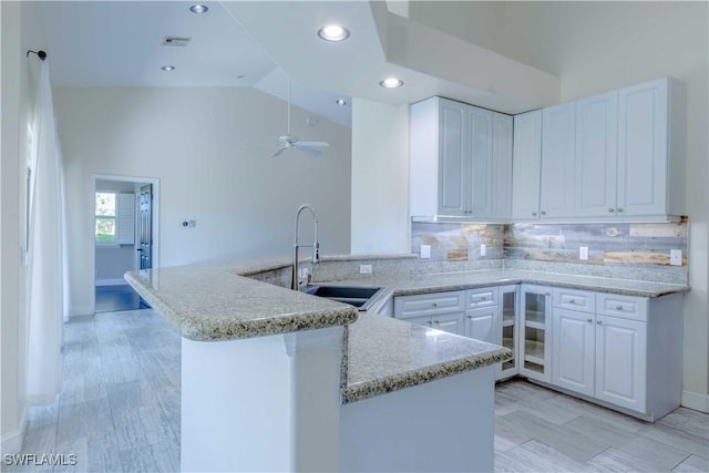 20730 Groveline Ct, Estero, FL 33928 - kitchen featuring a peninsula, white cabinetry, recessed lighting, tasteful backsplash, and light stone countertops
