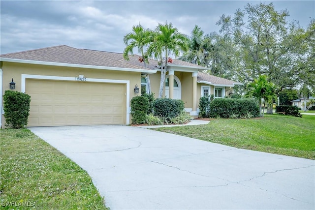 ranch-style house with concrete driveway, an attached garage, a front lawn, and stucco siding