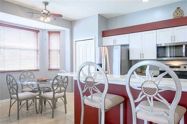 kitchen with white cabinets, ceiling fan, light tile patterned flooring, and stainless steel appliances