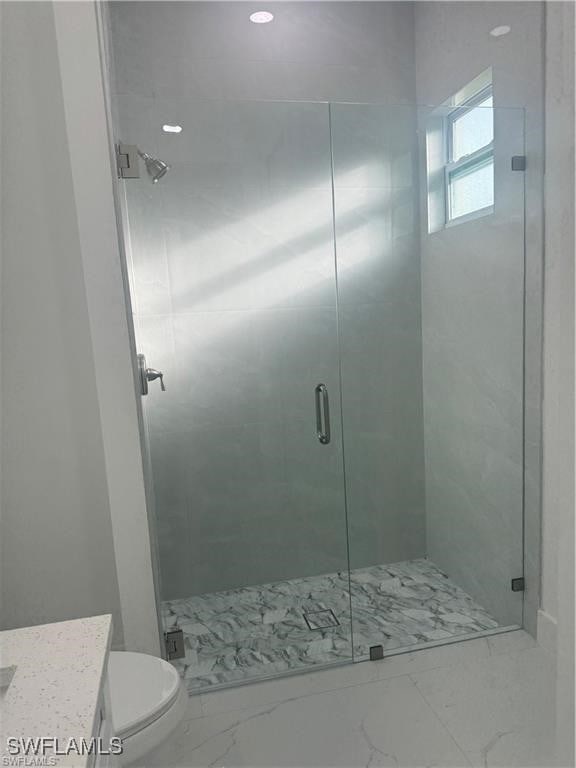 bathroom with walk in shower, vanity, and toilet