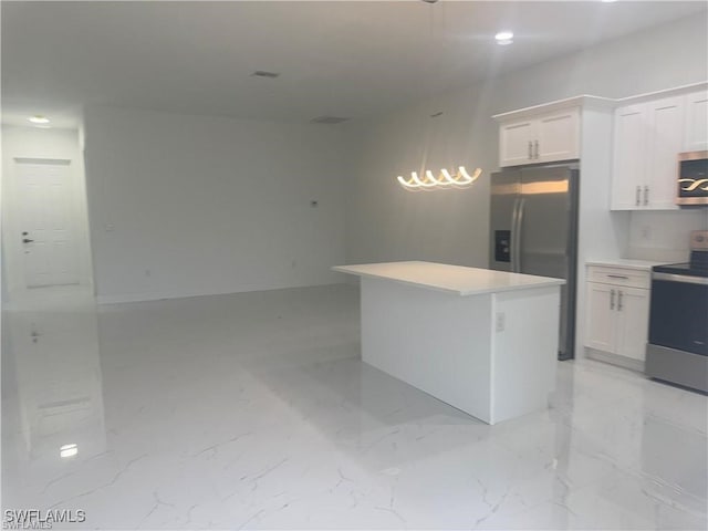 kitchen featuring white cabinets, appliances with stainless steel finishes, decorative light fixtures, and a center island