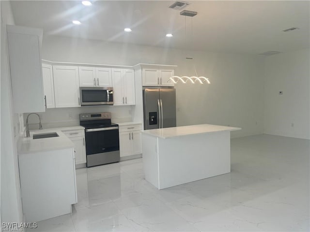 kitchen with pendant lighting, appliances with stainless steel finishes, sink, and white cabinets