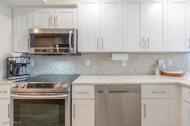 kitchen featuring appliances with stainless steel finishes, tasteful backsplash, light stone countertops, and white cabinets