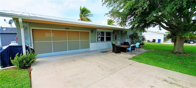 view of front of home with concrete driveway, a patio area, a front lawn, and metal roof