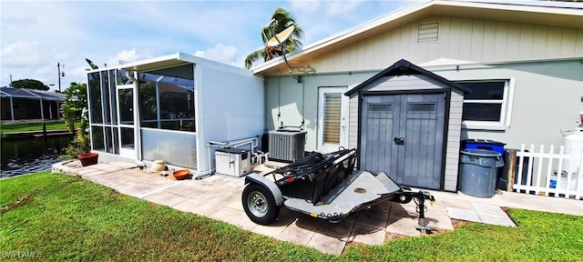 exterior space featuring central air condition unit, a lawn, a shed, and fence