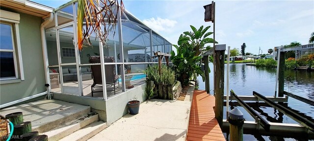 exterior space featuring a water view, a dock, and glass enclosure