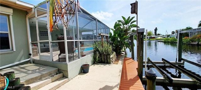 dock area with a water view, glass enclosure, boat lift, an outdoor pool, and a patio