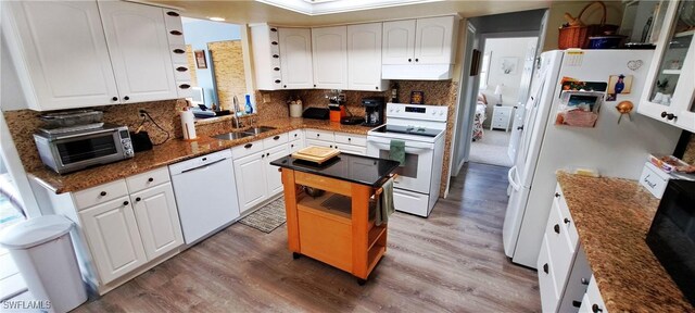 kitchen featuring white cabinetry, sink, white appliances, and wood-type flooring