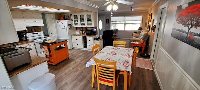 kitchen featuring crown molding, under cabinet range hood, white cabinets, white appliances, and dark wood-style flooring