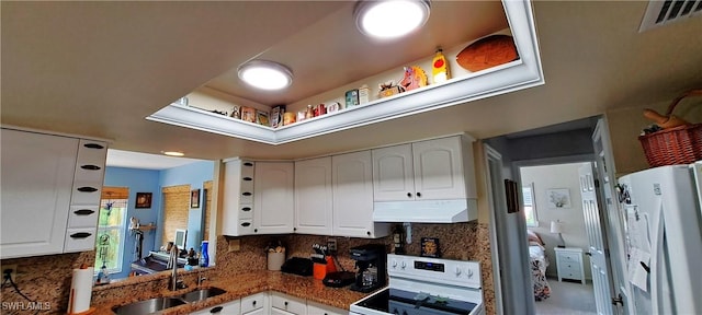 kitchen with under cabinet range hood, a sink, white cabinetry, freestanding refrigerator, and range