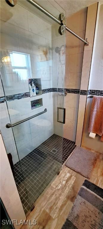 full bathroom featuring wood finished floors and a stall shower