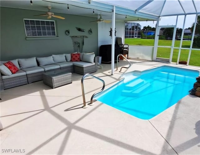 view of pool featuring glass enclosure, a patio, a ceiling fan, outdoor lounge area, and a lawn