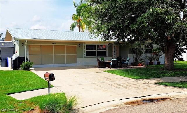 single story home featuring concrete driveway, a front yard, a garage, and metal roof