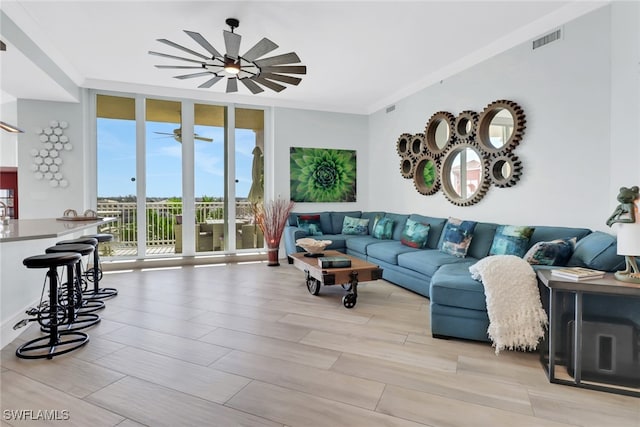 living room featuring crown molding, light wood-type flooring, and a wall of windows