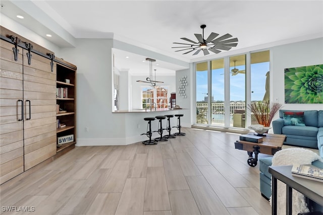 living room with light hardwood / wood-style floors, crown molding, a barn door, and floor to ceiling windows