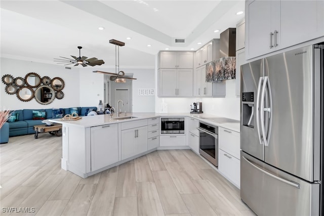 kitchen with kitchen peninsula, white cabinets, appliances with stainless steel finishes, light hardwood / wood-style floors, and sink