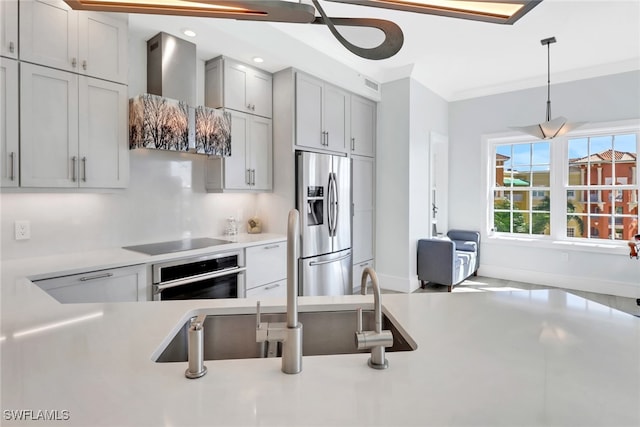 kitchen with gray cabinetry, wall chimney range hood, appliances with stainless steel finishes, sink, and crown molding