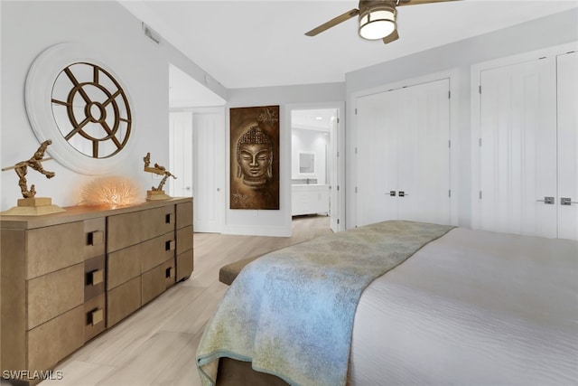 bedroom with ceiling fan, multiple closets, and ensuite bath