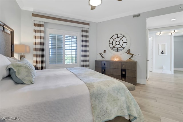 bedroom featuring ceiling fan, crown molding, and light hardwood / wood-style flooring