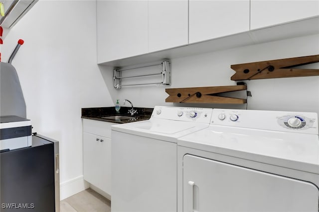 laundry room featuring sink, washing machine and clothes dryer, and cabinets