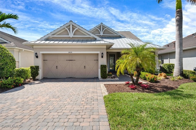 view of front of home with decorative driveway, a standing seam roof, metal roof, and stucco siding