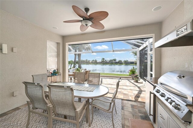 dining space featuring a water view, a sunroom, a ceiling fan, and a textured wall