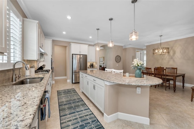 kitchen with a kitchen island, stainless steel appliances, white cabinetry, pendant lighting, and a sink