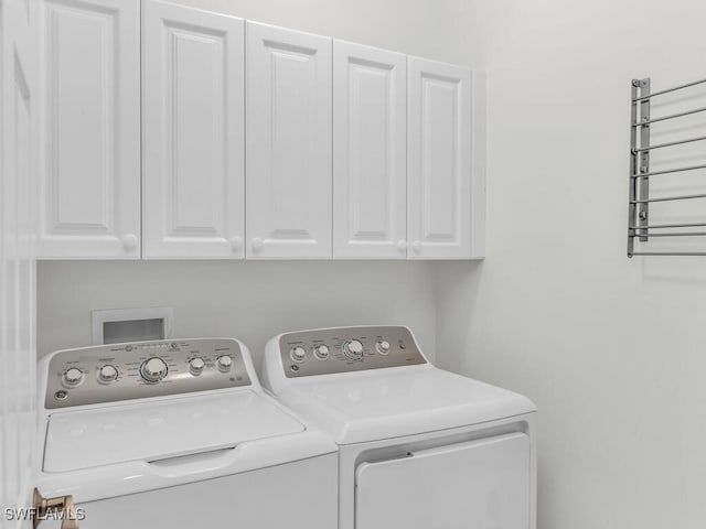 washroom with washing machine and clothes dryer and cabinets