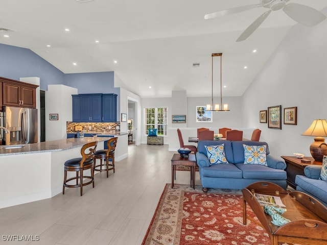 living room with light hardwood / wood-style flooring, vaulted ceiling, ceiling fan, and sink