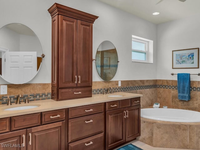 bathroom featuring tiled tub and vanity