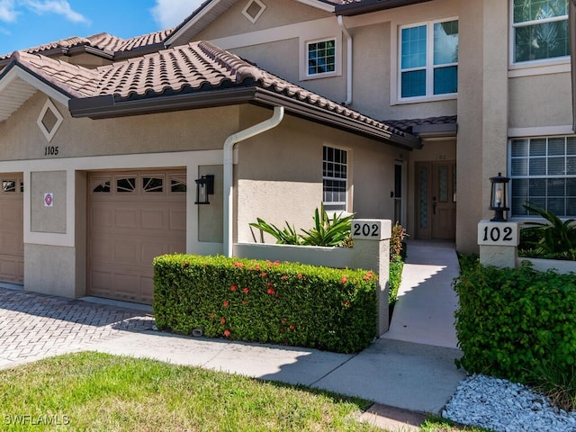 1105 Gayer Way Unit A-202, Marco Island, FL 34145 - view of front of house featuring stucco siding, an attached garage, a tiled roof, and driveway