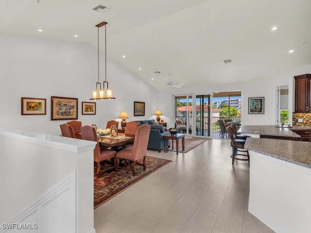 living room with light tile patterned flooring, ceiling fan with notable chandelier, and high vaulted ceiling