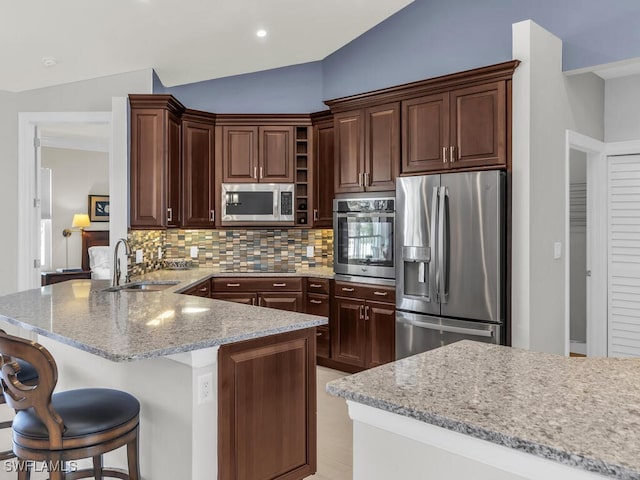 kitchen featuring sink, lofted ceiling, kitchen peninsula, backsplash, and appliances with stainless steel finishes