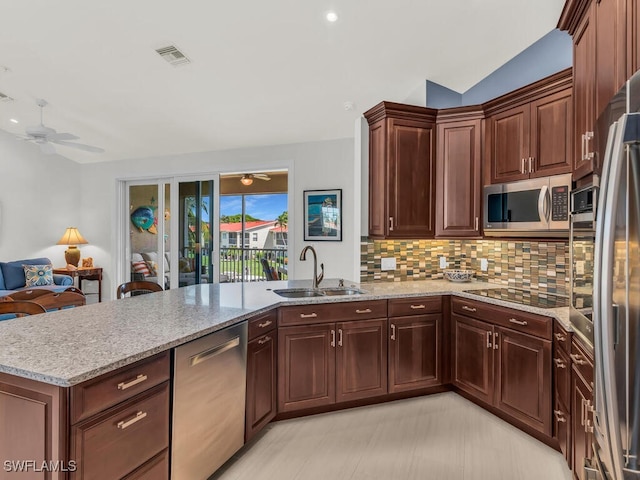 kitchen featuring ceiling fan, sink, kitchen peninsula, tasteful backsplash, and stainless steel appliances