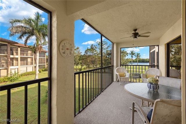 sunroom featuring a water view and ceiling fan