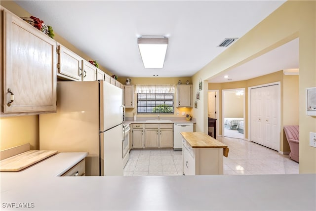 kitchen with sink, kitchen peninsula, butcher block counters, white appliances, and light brown cabinetry