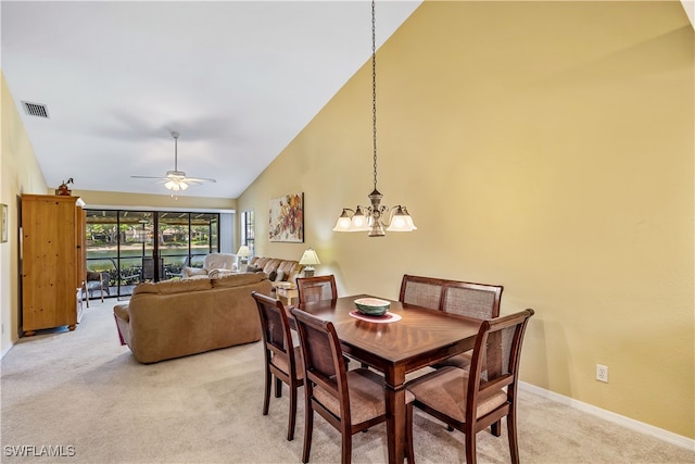 carpeted dining room featuring ceiling fan with notable chandelier and high vaulted ceiling