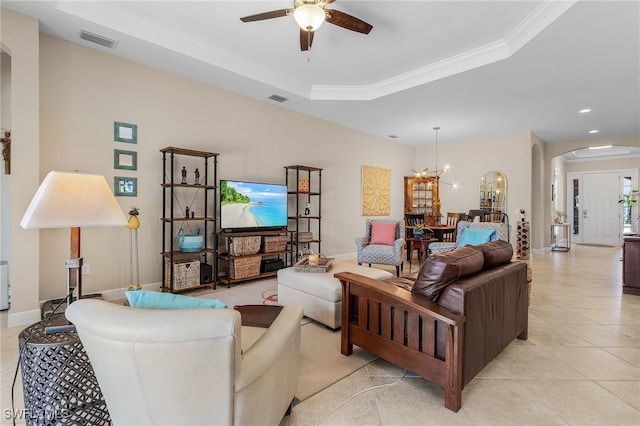 living room with a raised ceiling, light tile patterned floors, ceiling fan with notable chandelier, and ornamental molding